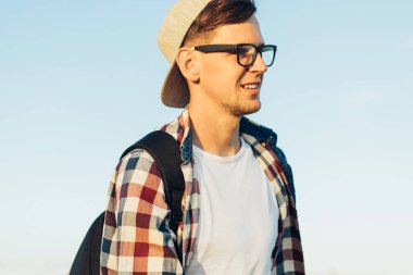 Sırt çantalı genç adam, yazın doğayı keşfeder, tepeleri ve tepeleri gezer, büyük bir sırt çantasıyla gezer, ormanlarda gezer, yaz manzarası