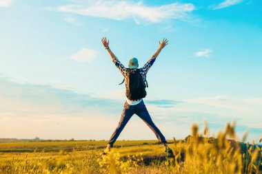 Elleri havada bir gezgin yeşil çimlerde bir tepede duruyor ve görkemli bir günbatımının tadını çıkarıyor zaferin tadını çıkaran başarılı bir adam, spor ve başarı kavramı, seyahat...