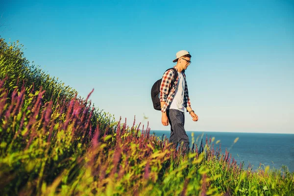 셔츠와 안경을 젊은이는 배낭을 등산을 미소짓는 남자는 언덕을 오르고 라이프 — 스톡 사진