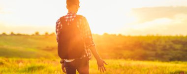 Sırt çantalı genç bir adam, çimde kır çiçekleriyle, arka planda Zakta 'nın, seyahat, doğa, turizm, orman kavramına karşı.