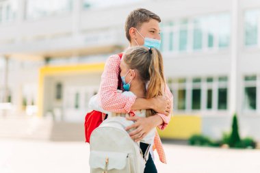 Koronavirüs salgını ve grip salgını sırasında maske takan çocuklar, çocuklara yönelik hastalıklardan korunma, karantina ve COVID-19 'dan izolasyon sonrası okula dönme, okul bahçesindeki bir okulun önündeki okul çocukları.