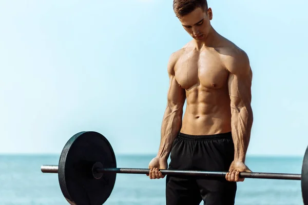 Hombre Musculoso Entrenando Playa Junto Mar Haciendo Ejercicios Con Una —  Fotos de Stock