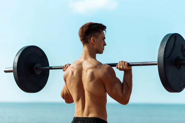 Hombre Musculoso Entrenando Playa Junto Mar Haciendo Ejercicios Con Una —  Fotos de Stock