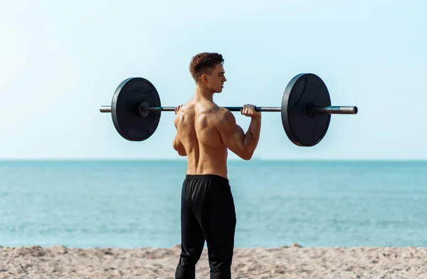 年轻的肌肉发达的男子在海滩上做胸肌锻炼 哑铃的重量很大 在户外 英俊的男子肌肉很大 摆出一副姿势 — 图库照片