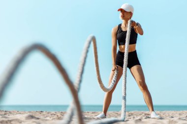 Spor için spor ipleri kullanan sporcu kadın, gün doğumunda plajda dövüş ipleriyle egzersiz yapan sporcu, deniz kenarında egzersiz yapan, sabah havasının tadını çıkaran sporcu, sağlık konsepti.