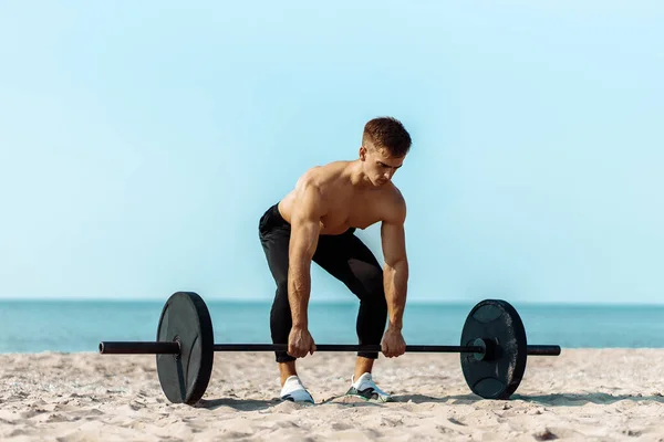 健康なハンサムなアクティブな男性でフィット筋肉の体 若い筋肉の男はウェイトを持ち上げ 練習を行い ビーチで運動スポーツマン 屋外トレーニング スポーツとフィットネスの概念 — ストック写真