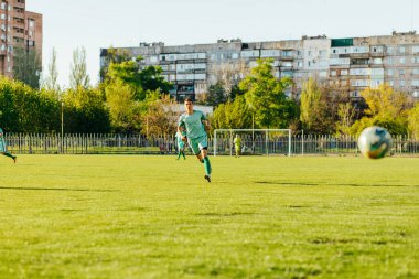 Futbolcu, profesyonel bir stadyumda, bir grup genç futbolcunun açık kortta oynadığı dinamik bir oyun oynar. Profesyonel spor konsepti, futbol