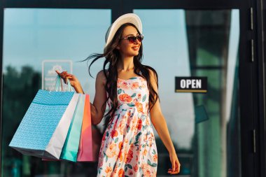 Alışveriş torbaları içinde, yaz kıyafetleri içinde, mağazadan ayrılıyor, yaz alışverişi konsepti, tüketicilik...