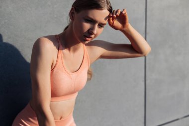 Aktif spor yaptıktan sonra dinlenen genç bir kadın fotokopi alanı olan gri duvarın karşısında duruyor, açık havada spor yaptıktan sonra dinlenen sağlıklı bir kadın.
