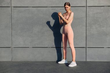 Formda genç bir kadının çömelme hareketleri, açık havada popo egzersizleri, kentsel beton arka planda egzersiz, sabahları dışarıda spor yapan fitness kadınları.