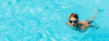 Güneş gözlüklü çocuk havuzda yüzüyor, havuzda oynayan mutlu çocuk, yaz tatili konsepti, top portresi.