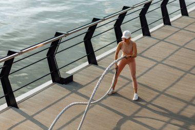 Spor salonundaki kadın iskelede spor ipleri kullanıyor, sporcu kadın dövüş ipleri, spor konsepti, sağlıklı yaşam tarzı kullanıyor.