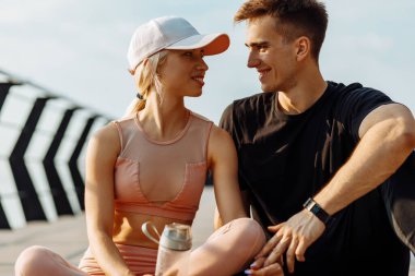 Sağlıklı çift dışarıda sıkı çalıştıktan sonra dinleniyor, birlikte egzersiz yapıyor, erkek ve kadın iskelede fitness dersinden sonra dinleniyor.