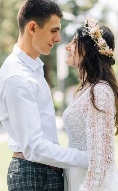 Mutlu genç çift, gelin ve damat düğün günlerinde düğün çifti yeni aile, gelinlik giymiş gelin ve çiçek buketi, parkta açık havada, Boho düğünü.