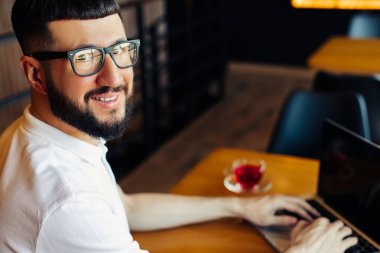 Yakışıklı ve başarılı bir adamın portresi, çay içip bir kafede dizüstü bilgisayara bakarken, bir iş adamının bir kafede kahvaltı ederken, bir dizüstü bilgisayar kullanırken, internette gezinirken.