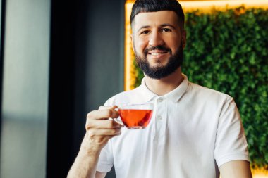 Genç, yakışıklı, sakallı, kahve molasında aromatik çay içen genç bir iş adamı.