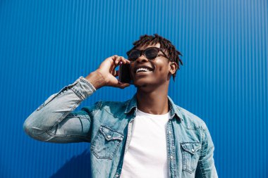 Siyah Afrikalı bir adam, telefonda konuşuyor, mavi bir binanın arka planında, ve başarı konsepti, telefonu olan bir öğrenci.