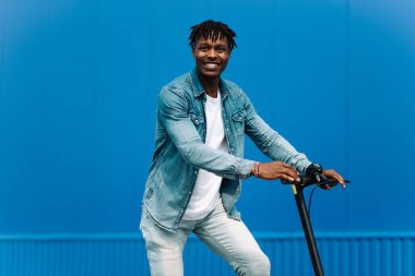 Modern Afro-Amerikan motosikletli, iş adamı çalışanlardan biri, öğrenci çalışanlardan biri, mavi bir binanın arka planında.