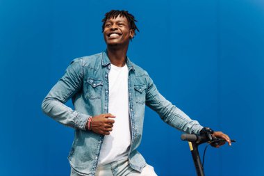 Modern Afro-Amerikan motosikletli, iş adamı çalışanlardan biri, öğrenci çalışanlardan biri, mavi bir binanın arka planında.