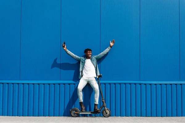 Afroamericano Con Scooter Eléctrico Muestra Gesto Éxito Sosteniendo Teléfono Mano — Foto de Stock