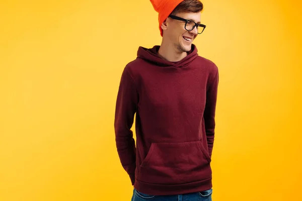주황색 모자를 스웨터와 안경을 배경에 잘생긴 남자의 초상화 — 스톡 사진
