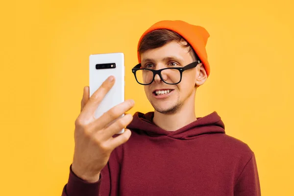 주황색 모자에 안경을 멋지고 스웨터를 눈으로 핸드폰을 해제하고 장치를 — 스톡 사진