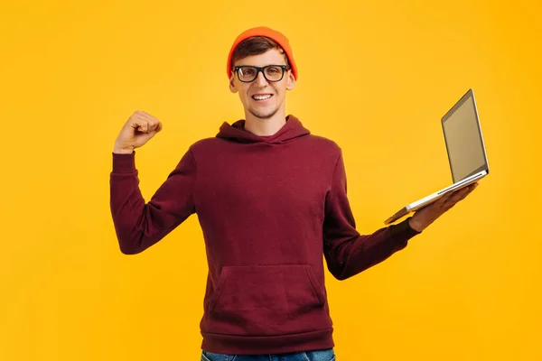 Jóképű Férfi Narancssárga Kalapban Szemüveggel Piros Pulóverrel Bemutatja Sikert Laptopokkal — Stock Fotó