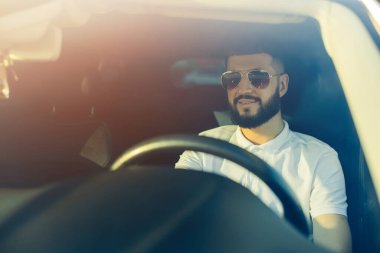 Yola odaklan, ön manzara, genç yakışıklı adam araba sürerken dik dik bakıyor.