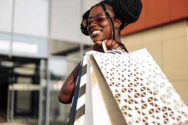 Tasasız, modaya uygun, gözlüklü, alışveriş torbalı, çantalı mutlu bir kadının portresi. Alışveriş, Kara Cuma, satış.