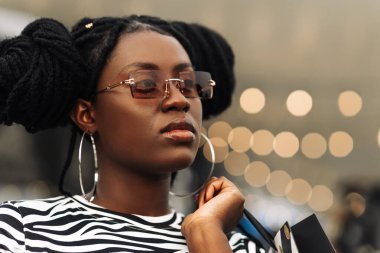 Gülümseyen siyah bir kadının portresi, gözlük takıyor, alışveriş torbaları, alışveriş merkezleri, alışveriş konsepti, tüketim