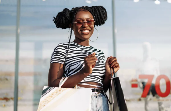 Schöne Lockige Afroamerikanerin Trägt Sonnenbrille Steht Mit Einkaufstüten Der Hand — Stockfoto