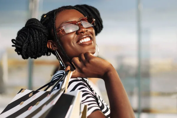 Schöne Lockige Afroamerikanerin Trägt Sonnenbrille Steht Mit Einkaufstüten Der Hand — Stockfoto