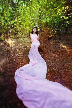 Çiçeklerle bir orman glade saçında pembe elbisenin içinde çok güzel bir kız