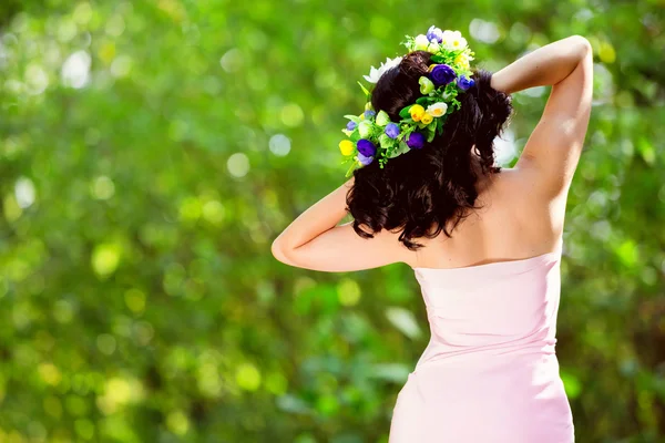 Ragazza molto bella in un abito rosa con i fiori tra i capelli in una radura della foresta — Foto Stock