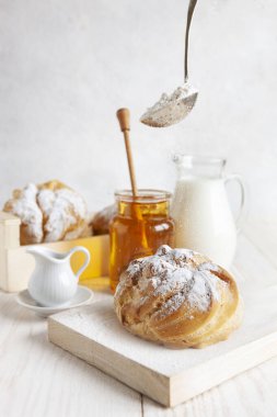 Kremalı çörekler, beyaz arka planda bir şişe süt ve bal. Günaydın aşk konsepti.