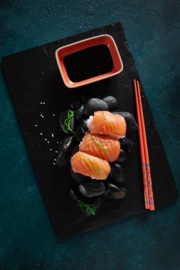Japon suşisi siyah taşlarda servis edilir. Üst görünüm, koyu arkaplanı kapat