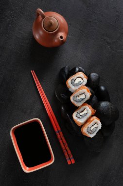 Japon suşisi siyah taşlarda servis edilir. Üst görünüm, koyu arkaplanı kapat