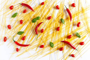 Geleneksel İtalyan makarna spagettisi, kiraz domatesleri, fesleğen ve kırmızı biber. Üst görünüm, yakın çekim, beyaz arkaplanda kopyalama alanı