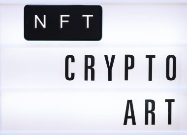 Mobil ekranda ve beyaz arkaplanda NFT kripto sanat yazıları. Yakın çekim, üst görünüm, boşluğu kopyala. 