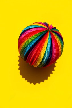 Sphere with a rainbow pattern on a bright yellow background, top view, close-up. clipart