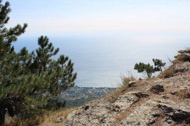 Kırım 'da sonbaharda Karadeniz' deki El-Petri dağından güzel bir manzara. Kırım 'daki dağların ve denizin manzarası. El-Petri Dağı 'nın tepesinde. Yüksek bir yerden Karadeniz manzarası. Su mavidir. Sonbaharda güneşli hava.
