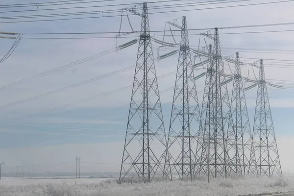 high-voltage power transmission towers on the background of a blue sky in winter / photo metal high-voltage towers. power lines. they are covered with frost. cold winter.