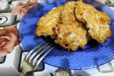 Lezzetli, sulu, peynirli tavuk pirzolası ve mavi tabakta ev yapımı yemek fotoğrafı. Tabakta üç tane tavuk pirzolası var. Meyve suyu için peynir eklenir.