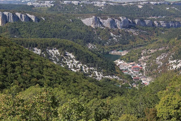Vadi manzarası, göl ve Mangup-Kale köyü Kırım 'daki dağlardan / fotoğraf dağ manzarası. Köy dağların arasında yer almaktadır. Kızıl çatılı evler. Gölün ortasında. Dağlar ormanla kaplı.. 