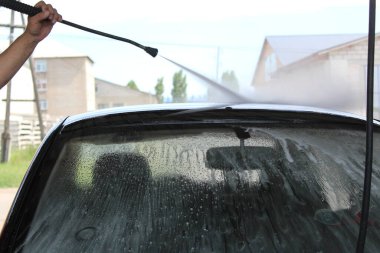 Bir adam bağımsız olarak bir araba kercher / fotoğraf yıkar bir adam bağımsız olarak bir araba yıkar. Elinde bir kercher var. Yüksek basınçlı su jeti. Araba siyah..