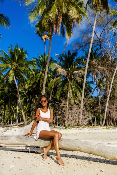 Krásná černá dospívající dívka sedí na palmy na pláži. — Stock fotografie