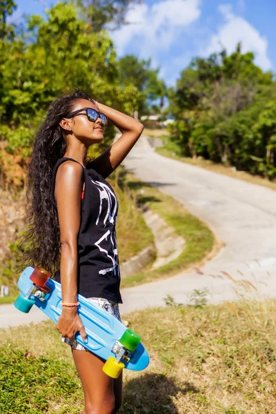 Retrato al aire libre de una adolescente negra con longboard azul ska —  Fotos de Stock