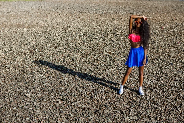 Черная девочка-подросток в голубой юбке и розовом бюстгальтере на голове — стоковое фото