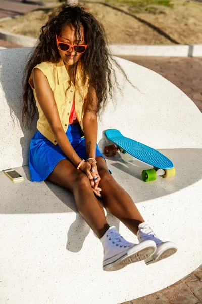 Schöne schwarze Teenager-Mädchen in blauem Rock sitzen mit ihrem Penny lo — Stockfoto