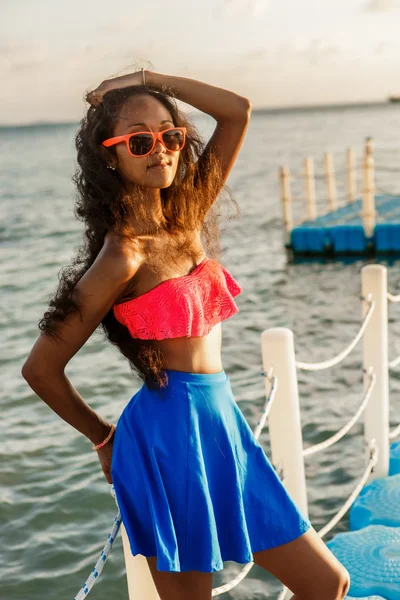 プラスチック桟橋で青いスカートの美しい 10 代の黒い少女. — ストック写真